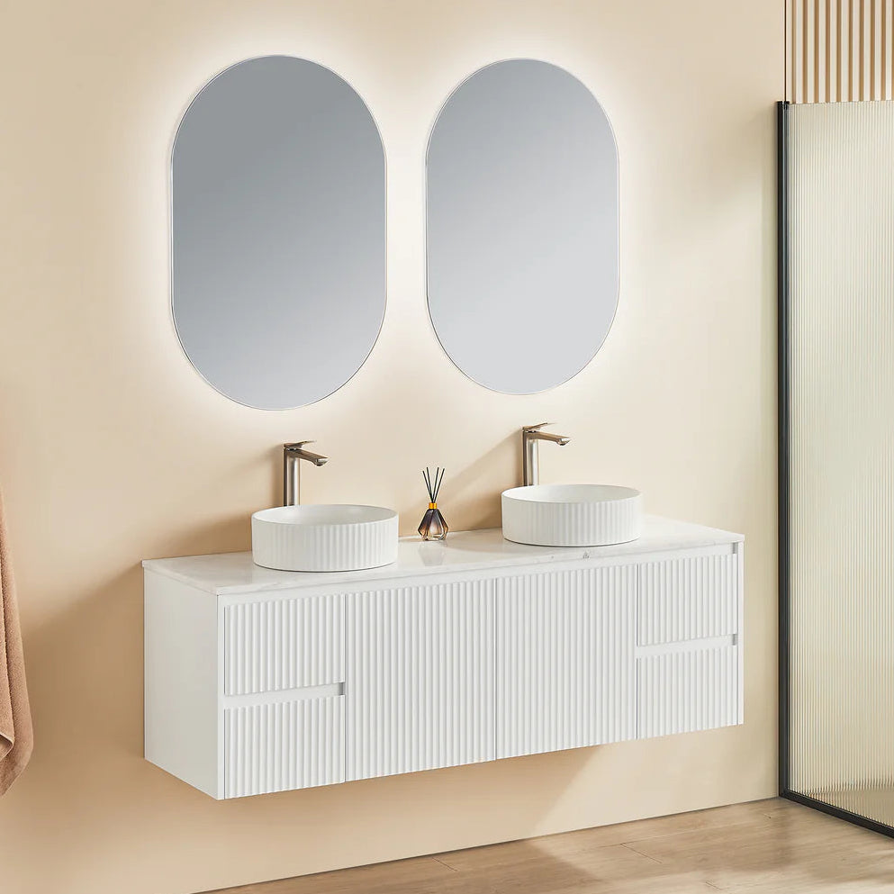 Bathroom with white vanity, double sinks, and two oval mirrors on a beige wall.