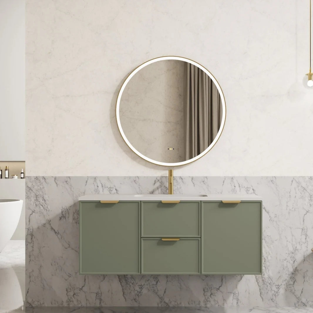 Bathroom vanity with round mirror and green cabinets against a marble wall.