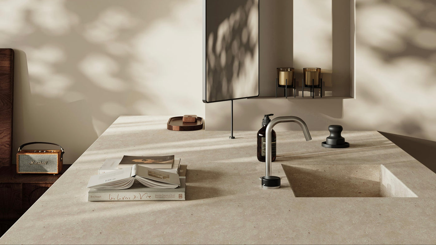 Modern kitchen sink with faucet and decorative items on a light-colored countertop.