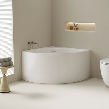 Stanford 1000mm triangle corner bath in gloss white installed in a bathroom corner, front view