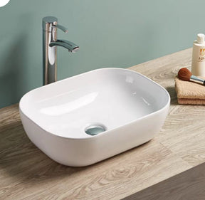 White oval sink on a wooden countertop with a silver faucet against a light green wall.